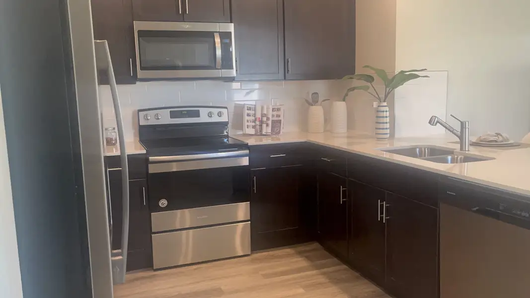 A modern kitchen with dark cabinetry, stainless steel appliances, and sleek fixtures.