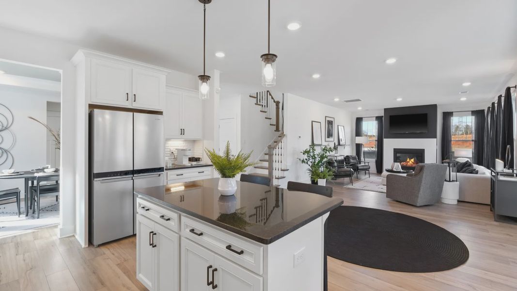 Modern black and white kitchen with white cabinetry, hardwood flooring, and tall ceilings at Fox Hollow by DRB Homes