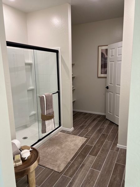 A sleek bathroom featuring a glass-enclosed shower, wood-style tile flooring, and minimalist decor.