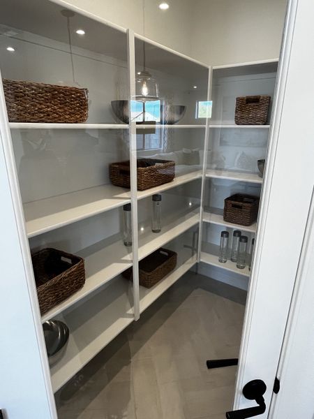 Open shelves with wicker baskets and glass containers create a clean and accessible storage space.