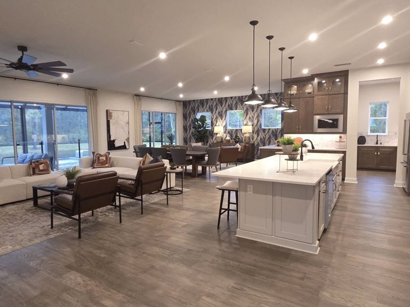 Spacious open-concept living area featuring sleek kitchen, island, cozy seating, and modern lighting. Ideal for entertaining.
