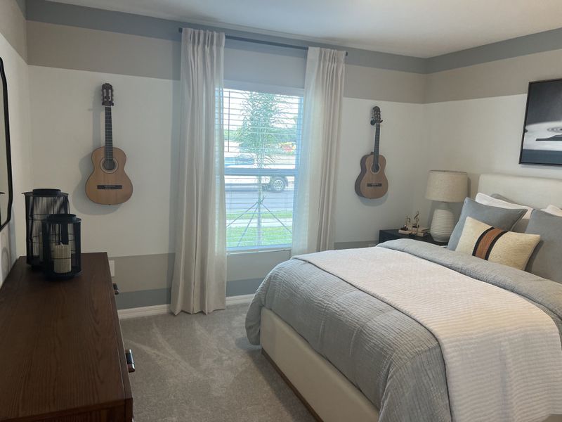 A cozy bedroom with elegant gray tones, a plush bed, and wall-mounted guitars adding a musical touch.