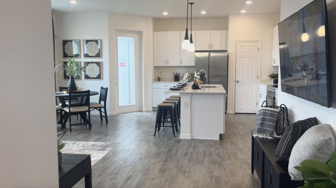 An open-concept kitchen and dining area with modern lighting, sleek cabinetry, and cozy seating.