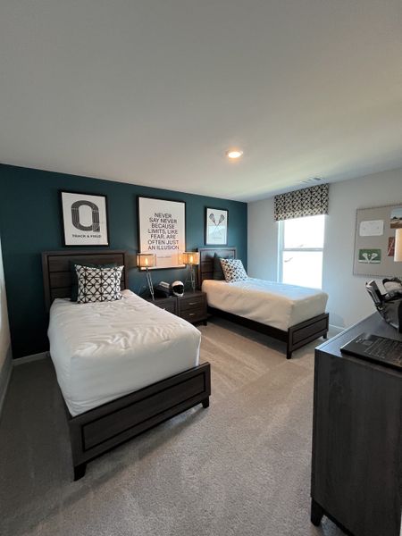 A cozy bedroom featuring twin beds, a deep teal accent wall, and modern decor for a comfortable, inviting atmosphere.