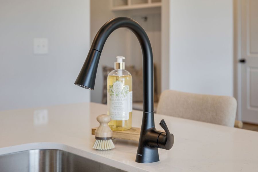 A faucet and a bottle of soap on a counter.