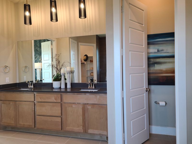 A modern bathroom with sleek wooden cabinetry, dual sinks, and elegant pendant lighting above. A modern bathroom with sleek wooden cabinetry, dual sinks, and elegant pendant lighting above.
