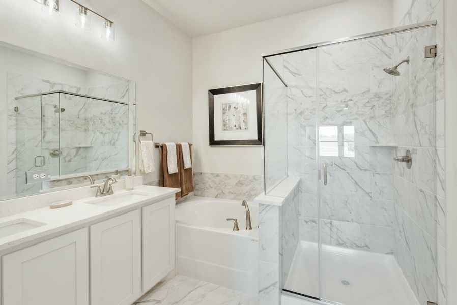 Bathroom with marble tile, glass walk-in shower, soaking tub, and white double vanity