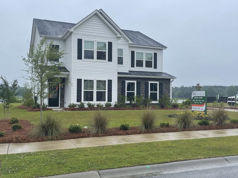 A charming white two-story home with black shutters and landscaped yard in Timothy Lakes by Center Park Homes (Ridgeville, SC).