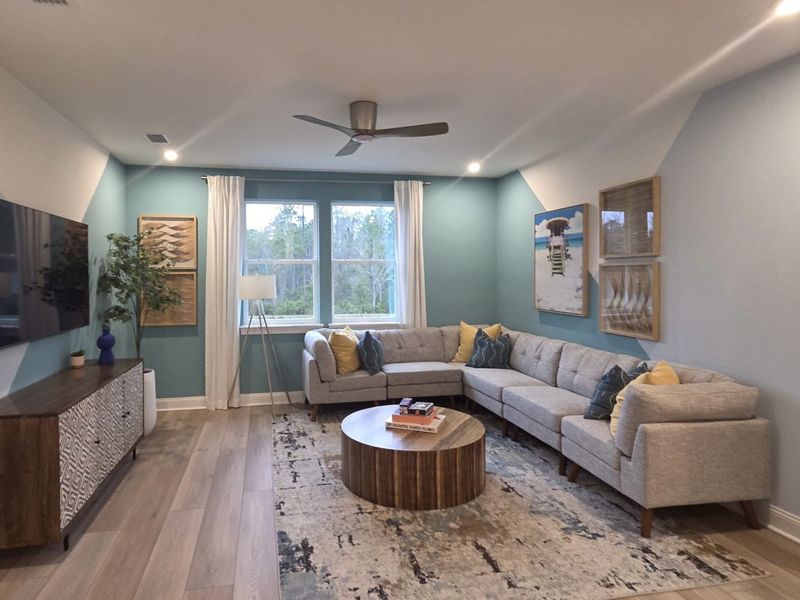 A cozy living room with a sectional sofa, blue accent wall, modern decor, and natural lighting from a large window. A cozy living room with a sectional sofa, blue accent wall, modern decor, and natural lighting from a large window.