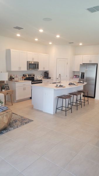 A modern kitchen featuring sleek white cabinets, a center island with seating, and stainless steel appliances.