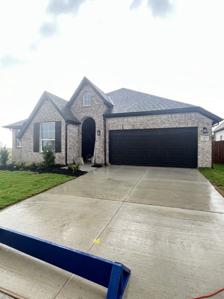 A charming brick home with dark shutters and a two-car garage in Elevon by Pacesetter Homes (Lavon, TX).