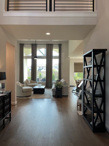 A spacious living area with elegant furniture, large windows, and sleek wooden flooring.