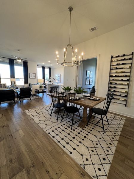 A stylish dining area with a rustic wood table, elegant chandelier, and open-concept layout.