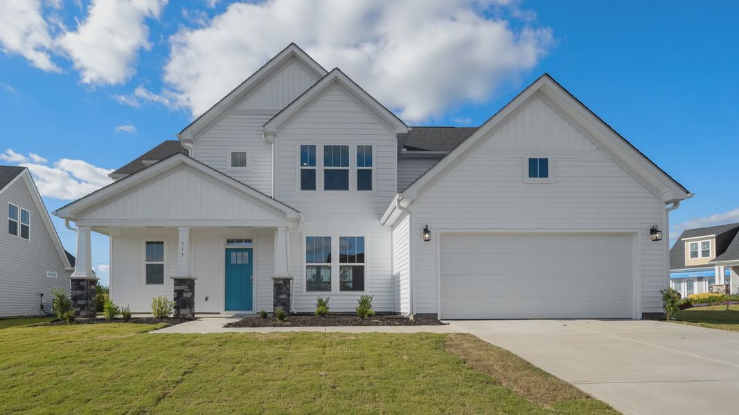 Arlington floorplan with bright white exterior, stone columns, blue door, and two car garage at Wells Crossing in Seneca, SC