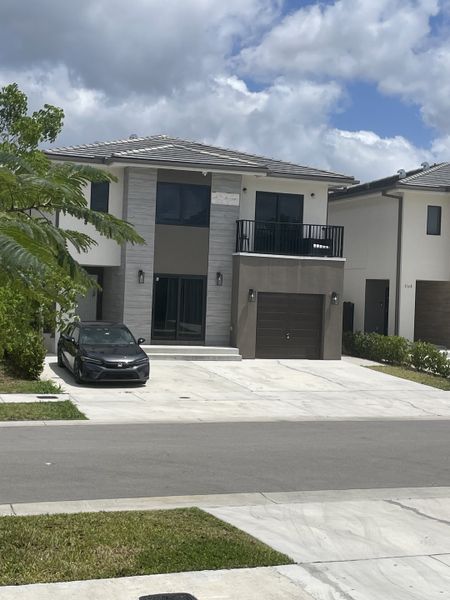 A modern two-story home with a sleek design and spacious driveway in On Alba by Onx Homes (Florida City, FL).