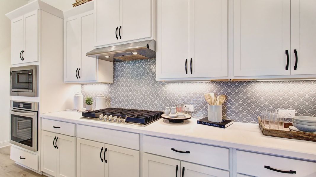 Experience luxury with custom white cabinetry and fish scale tile in Veranda’s sophisticated kitchen.
