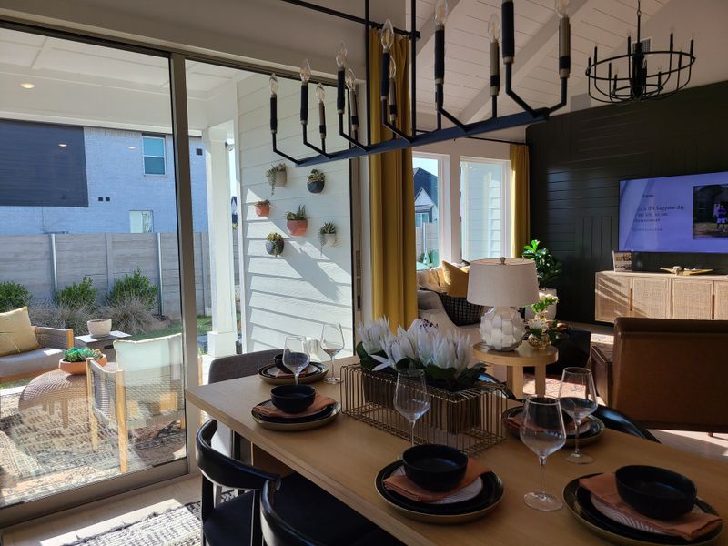 A modern dining and living area with elegant decor, natural light, and outdoor views through large sliding glass doors.