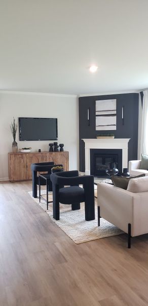 A modern living room featuring sleek chairs, a stylish fireplace, and a wooden console with decorative accents.