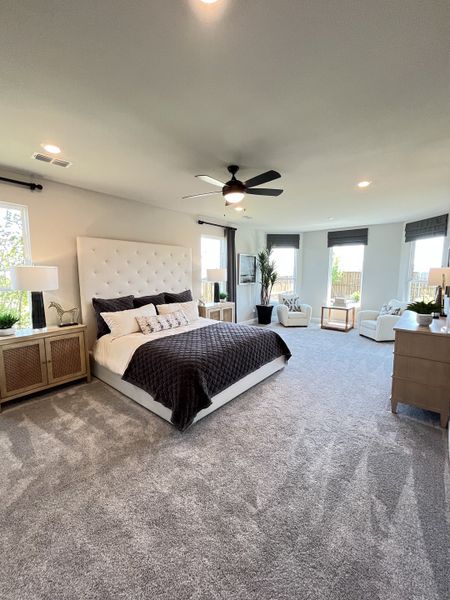 Spacious bedroom with plush carpeting, a tufted headboard, cozy seating, and abundant natural light. Spacious bedroom with plush carpeting, a tufted headboard, cozy seating, and abundant natural light.