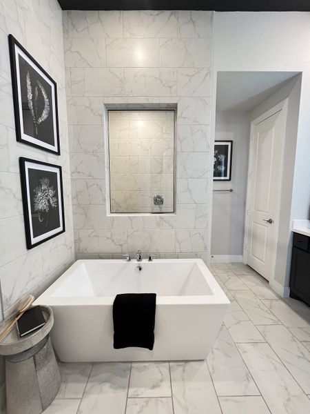 A modern bathroom with marble tile, a sleek white bathtub, and stylish framed artwork. A modern bathroom with marble tile, a sleek white bathtub, and stylish framed artwork.