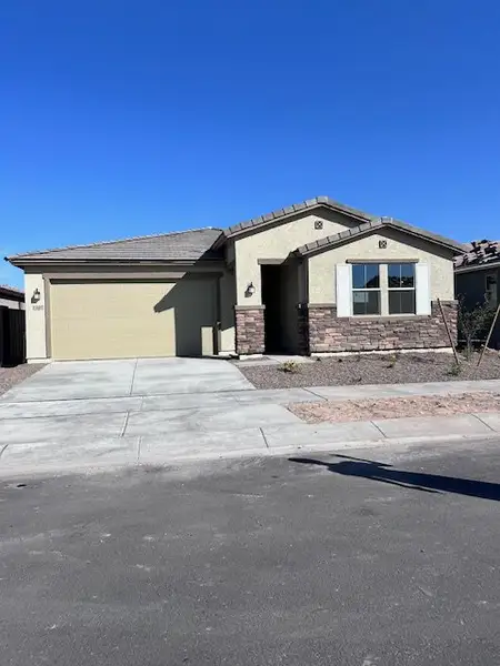 A modern beige home with stone accents in Ventana de Estrellas Enclaves by KB Home, Goodyear, AZ.