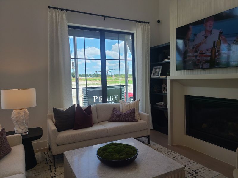 A cozy living room featuring a modern fireplace, plush seating, and large windows with abundant natural light.