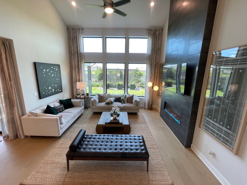 A modern living room with high ceilings, expansive windows, plush seating, and a sleek fireplace feature. A modern living room with high ceilings, expansive windows, plush seating, and a sleek fireplace feature.