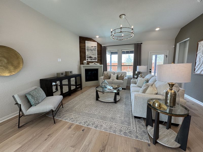 A spacious living room with a modern chandelier, cozy fireplace, light sofas, and elegant decor on hardwood floors. A spacious living room with a modern chandelier, cozy fireplace, light sofas, and elegant decor on hardwood floors.