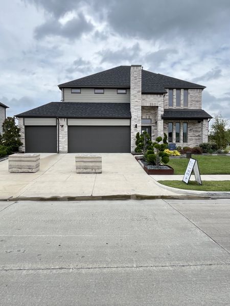 A modern gray brick home with sleek lines and a tidy garden in Lakehaven by Trophy Signature Homes (Farmersville, TX).