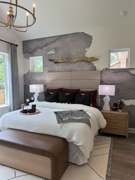 A cozy bedroom featuring an artistic accent wall, plush bedding, and warm lighting for a serene retreat.