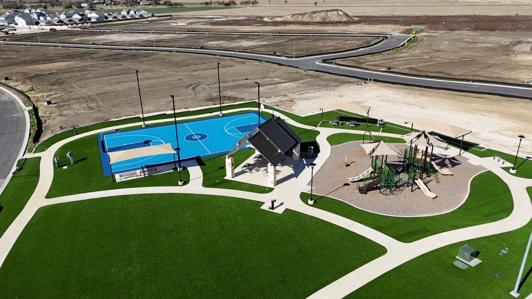 A vibrant park with a basketball court and playground in Cielo Gardens: Welton Collection by Lennar (Jarrell, TX).