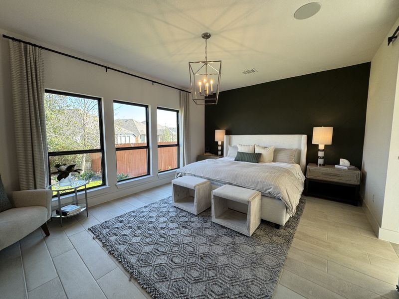 A serene bedroom featuring a dark accent wall, large windows, cozy bedding, and stylish lighting for a perfect retreat.