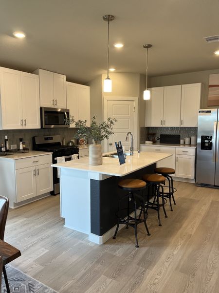 A modern kitchen featuring sleek cabinetry, a spacious island with seating, and contemporary lighting fixtures.