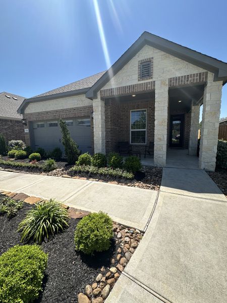 A charming brick home with a covered porch and landscaped garden in Wedgewood Forest by LGI Homes (Conroe, TX).