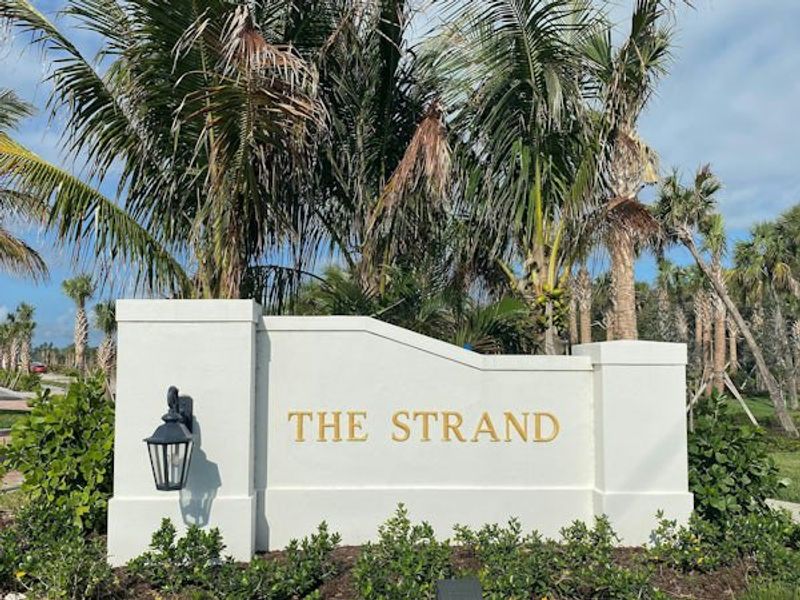 Entrance to the The Strand community in Vero Beach, FL, featuring signage and landscaping (Image 2).