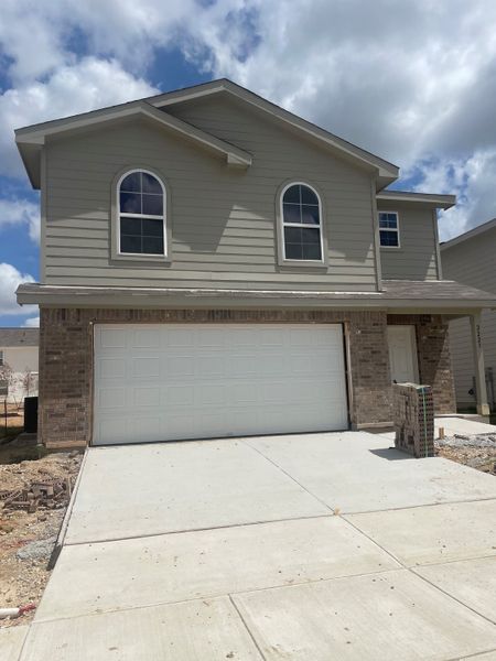 A charming two-story home with a brick exterior and arched windows at Hunter's Pond by National HomeCorp (San Antonio, TX).