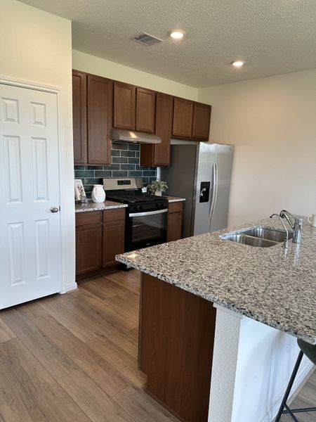 A modern kitchen featuring granite countertops, sleek stainless steel appliances, and stylish wood cabinetry.