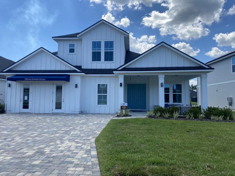 A modern white home with blue accents and landscaped yard in Holly Landing at SilverLeaf by Dream Finders Homes (St. Augustine, FL).
