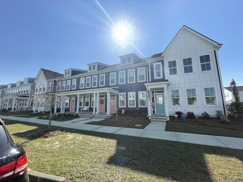 A row of modern townhomes with varied facades and colorful doors, in Townhomes at Nexton by Brookfield Residential in sunny Summerville, SC.