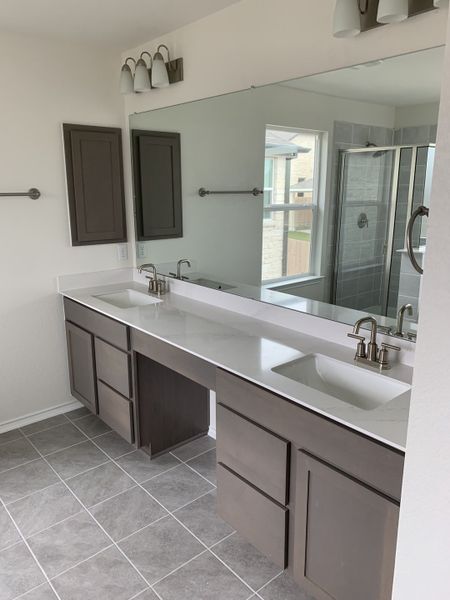 A modern bathroom with dual sinks, sleek cabinetry, and a large mirror, showcasing elegance and functionality.