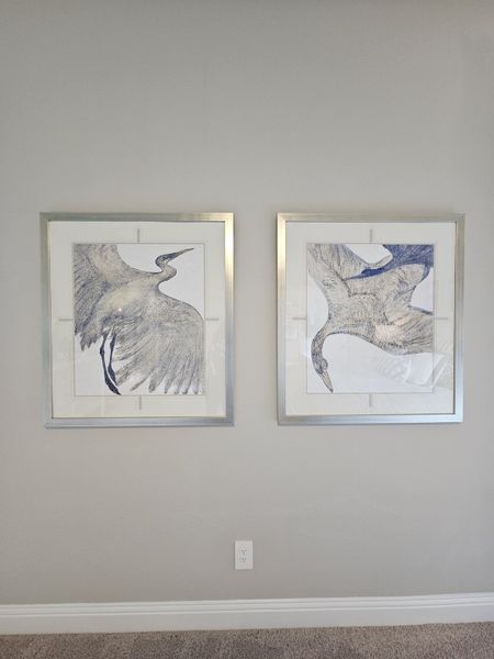 Elegant wall art featuring two framed bird illustrations with silver frames enhance this neutral-toned room. Elegant wall art featuring two framed bird illustrations with silver frames enhance this neutral-toned room.