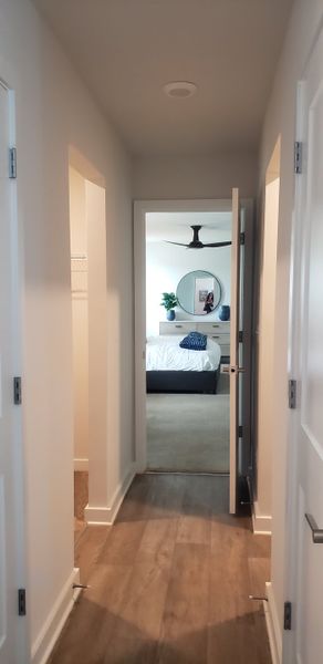 A cozy hallway leading to a bright bedroom featuring modern decor and a ceiling fan. A cozy hallway leading to a bright bedroom featuring modern decor and a ceiling fan.