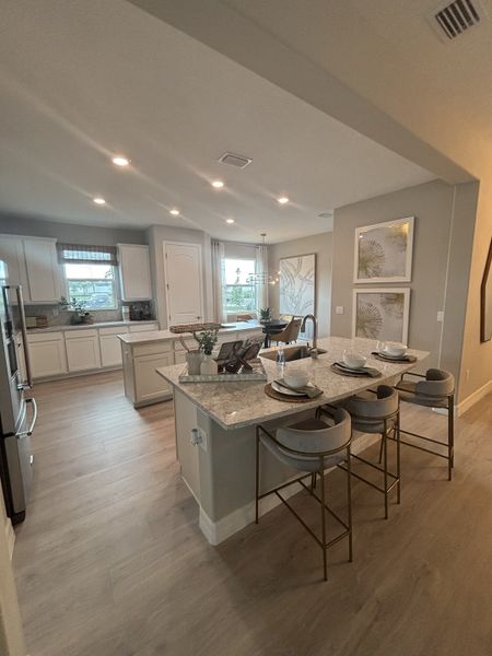 Open-concept kitchen with a spacious island, modern barstools, and elegant lighting.