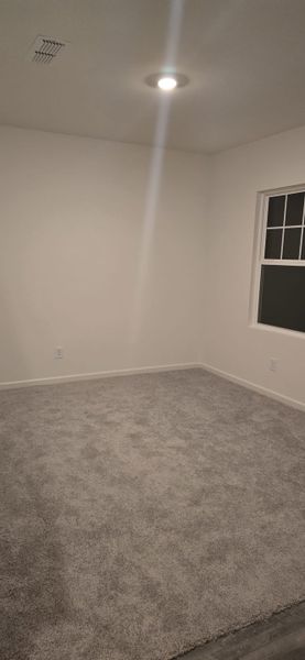 A cozy room with plush carpet, neutral walls, and recessed lighting, perfect for personalization and comfort.