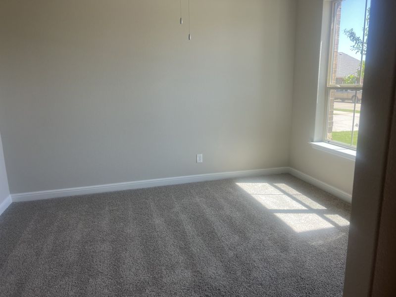 A sunlit carpeted room with neutral walls and a large window offers warmth and comfort. A sunlit carpeted room with neutral walls and a large window offers warmth and comfort.
