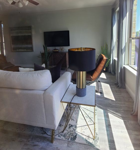 A bright living room with cozy seating, a modern lamp, and sunlight streaming through large windows. A bright living room with cozy seating, a modern lamp, and sunlight streaming through large windows.