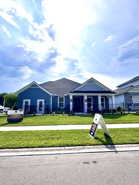 A charming blue home with a manicured lawn in Jennings Farm by Dream Finders Homes (Middleburg, FL).