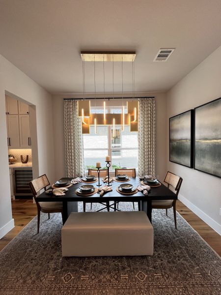 A chic dining room with a modern chandelier, elegant table setting, and cozy seating.