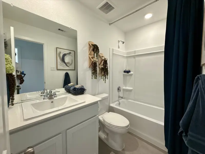 A modern bathroom with a sleek vanity, elegant decor, and a pristine bathtub surrounded by soothing tones.