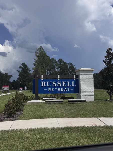 Welcome to Russell Retreat by Lennar in Green Cove Springs, FL. Lush greenery and a striking sign greet visitors.